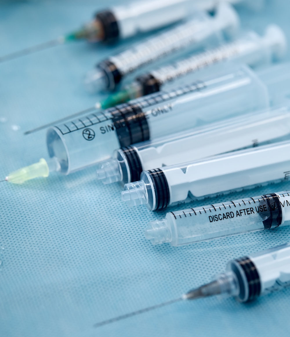 Medical syringes on a clinical blue drape, representing allergy shots in a doctor’s office