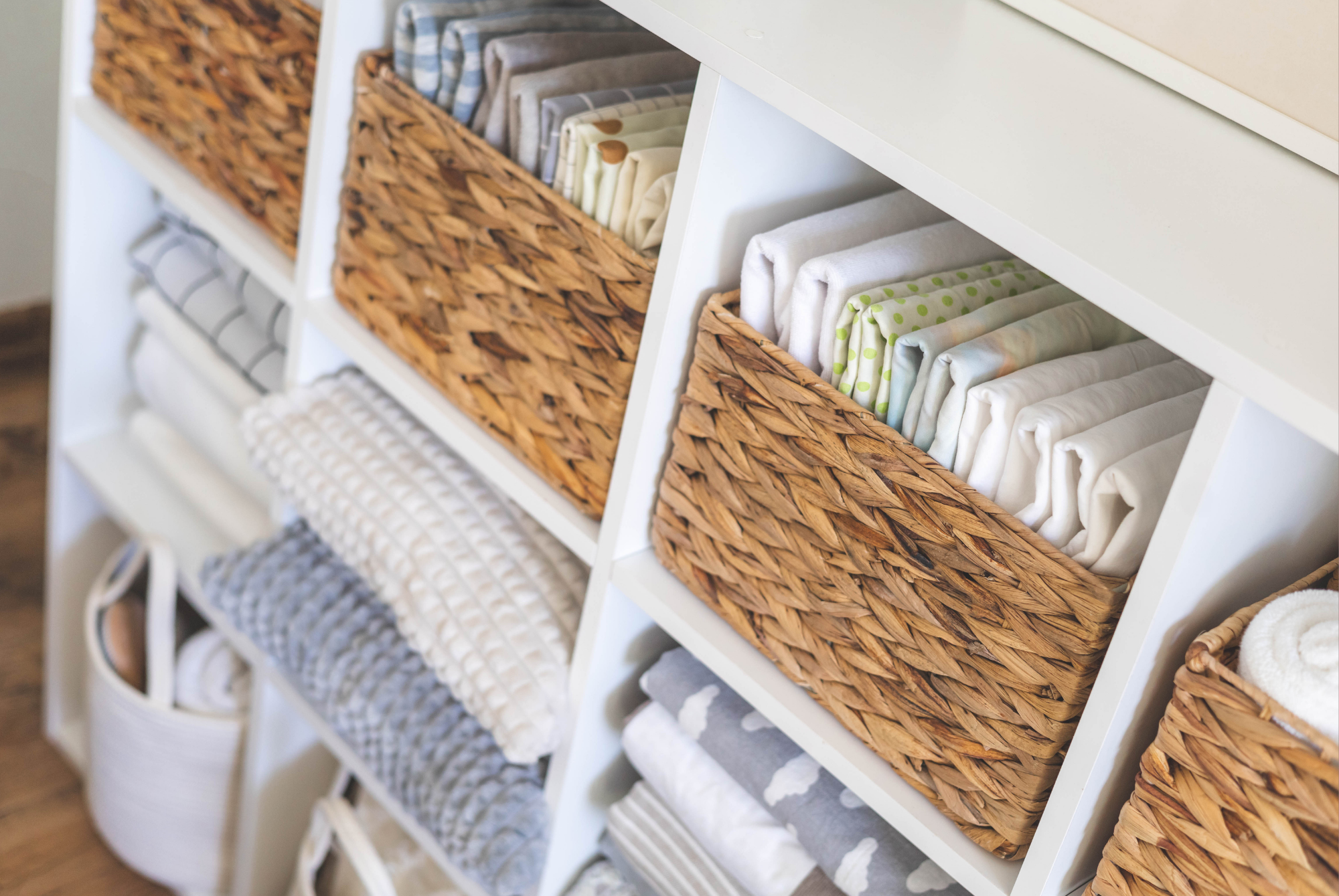Woven baskets and folded linens organized in a white cubby shelf